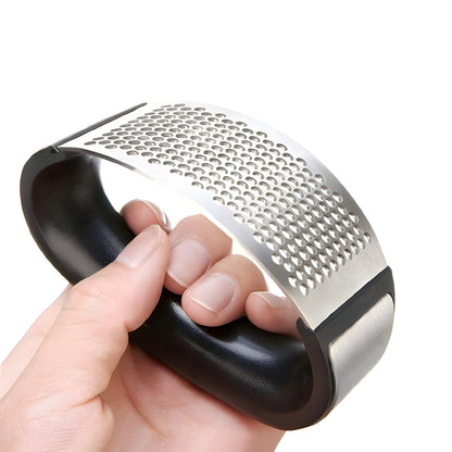 A hand holding a garlic press tool with a black handle and a silver metal perforated plate, shown against a plain white background.