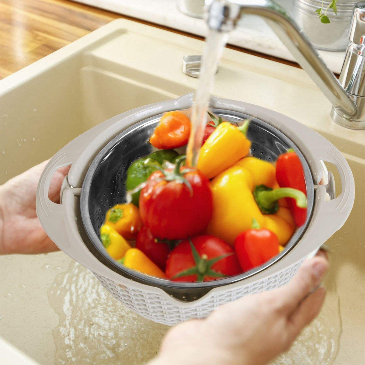 Colander with bell peppers being rinsed under running water in a kitchen sink.
